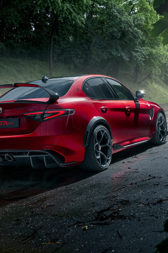 Красный автомобиль Alfa Romeo Giulia GTAm, 2021 года на дороге в лесу