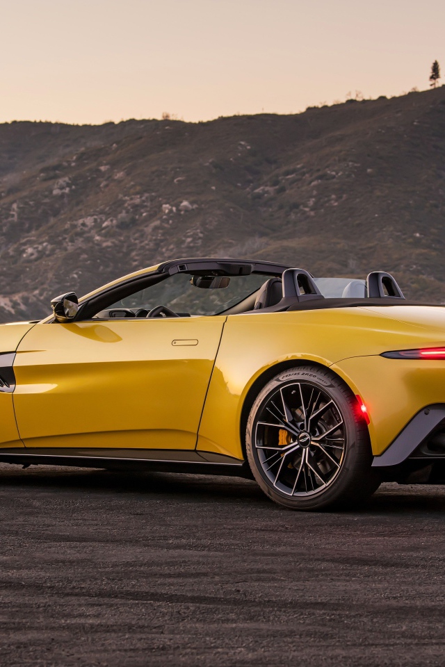 Желтый автомобиль  Aston Martin Vantage Roadster, 2021 года на фоне гор 