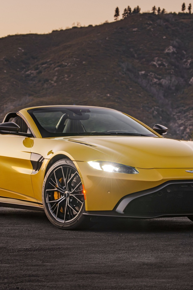 Желтый автомобиль  Aston Martin Vantage Roadster, 2021 года на фоне холмов