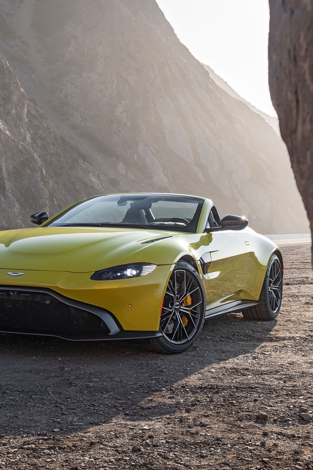 Желтый автомобиль  Aston Martin Vantage Roadster, 2021 года в горах 