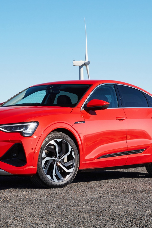 Красный автомобиль Audi E-Tron 50 Quattro Sportback S Line 2020 на фоне ветряных турбин