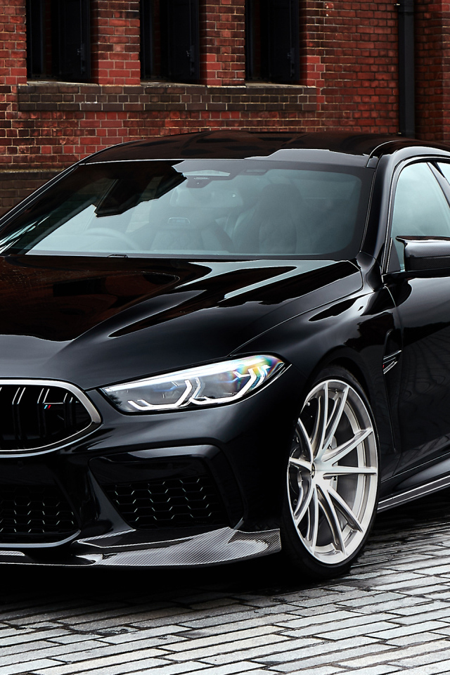 Дорогой черный автомобиль BMW M8 у стены