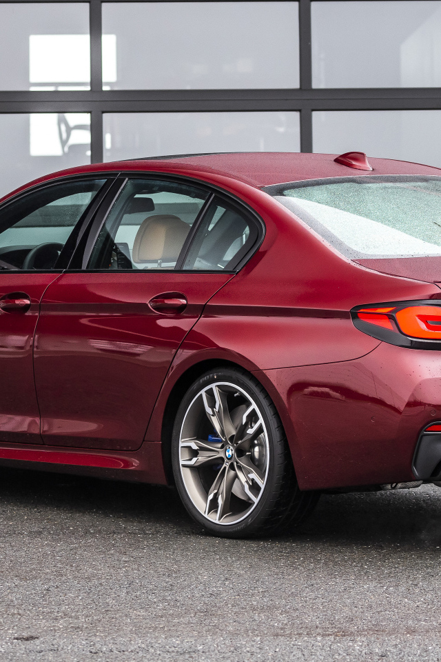 Красный автомобиль BMW M550i XDrive, 2021 года вид сзади