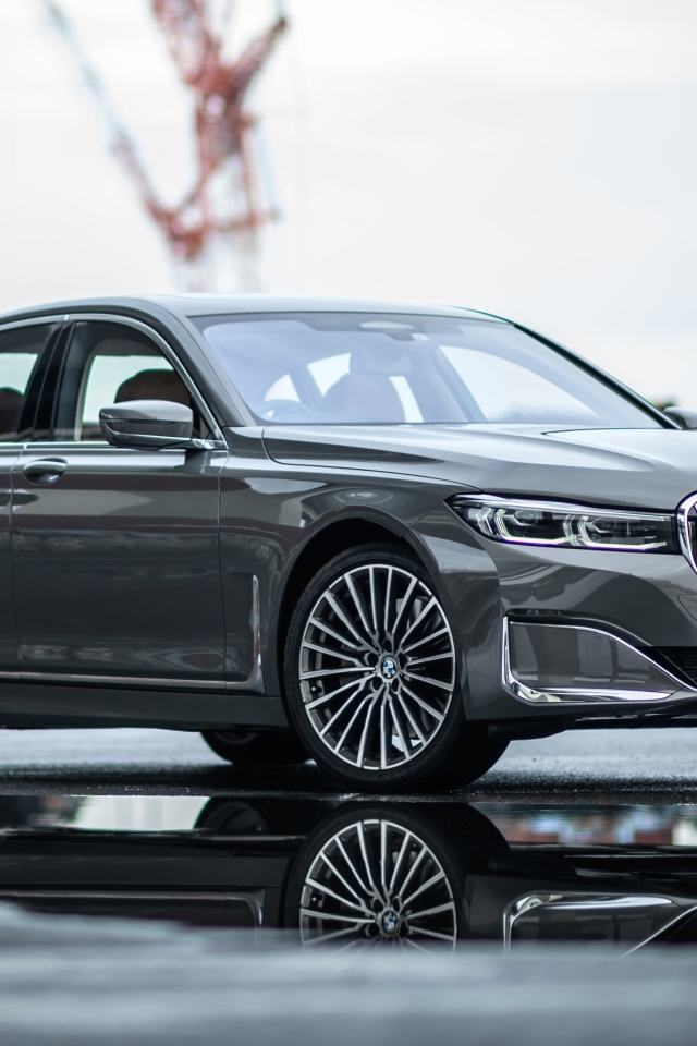 Серебристый автомобиль BMW 745e на мокром асфальте 