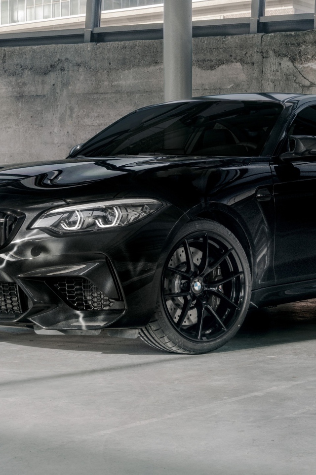 Черный автомобиль  BMW M2, 2020 года у бетонной стены