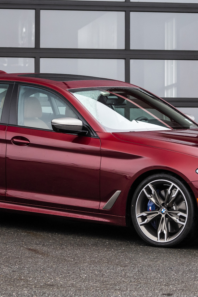 Красный автомобиль BMW M550i XDrive, 2021 года у гаража