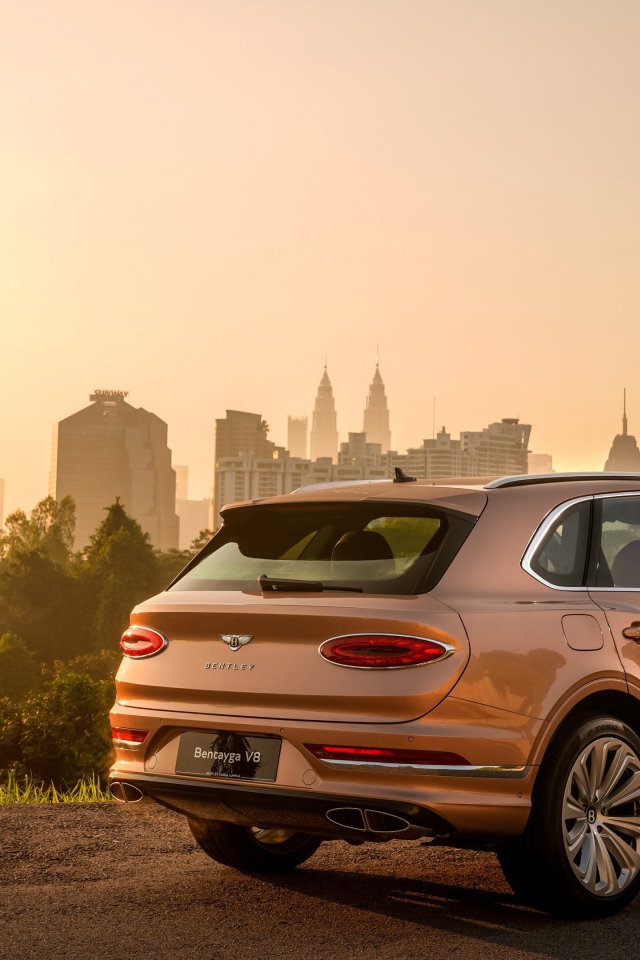 Автомобиль Bentley Bentayga V8 2020 года вид сзади на фоне города 