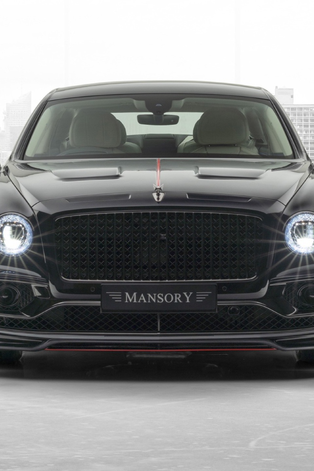 Черный автомобиль Mansory Bentley Flying Spur 2020 года с включенными фарами 