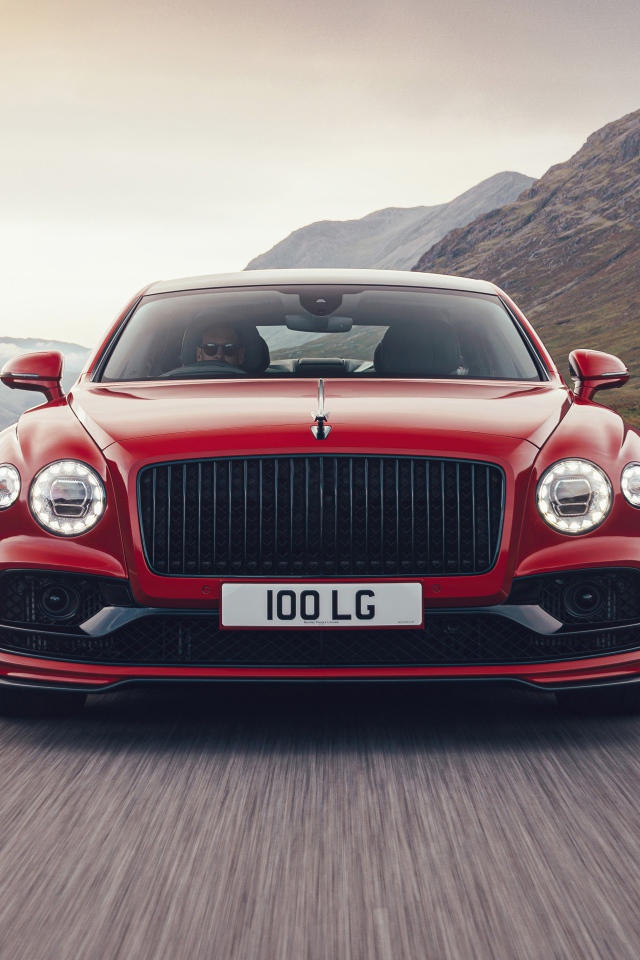 Красный автомобиль Bentley Flying Spur V8 2020 года на дороге в горах 