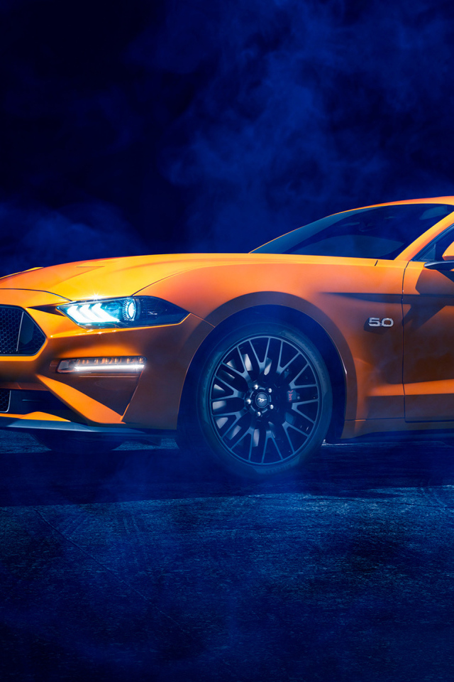 Оранжевый автомобиль Ford Mustang в дыму