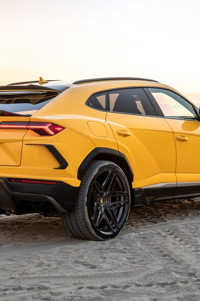 Желтый автомобиль  Lamborghini Urus на песке у моря