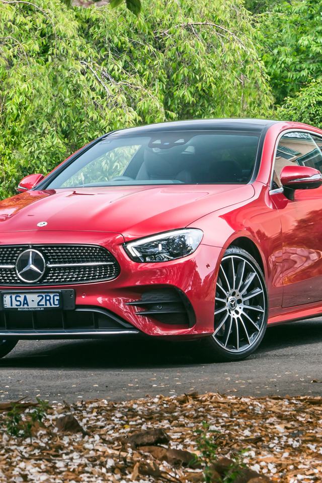 Красный автомобиль Mercedes-Benz E 300 AMG, 2020 года у дома осенью