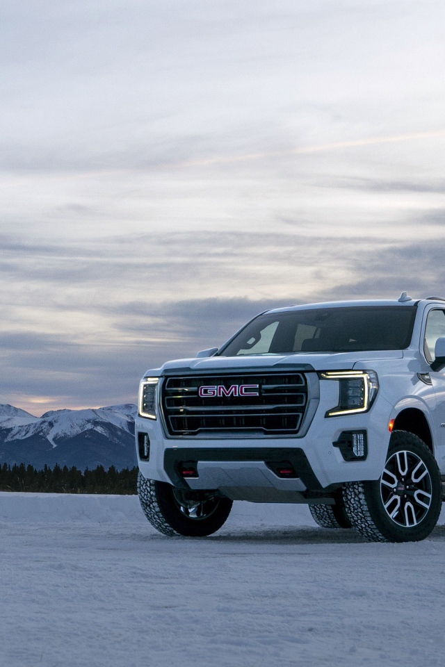 Белый внедорожник  GMC Yukon AT4, 2021 года на фоне заснеженных гор 
