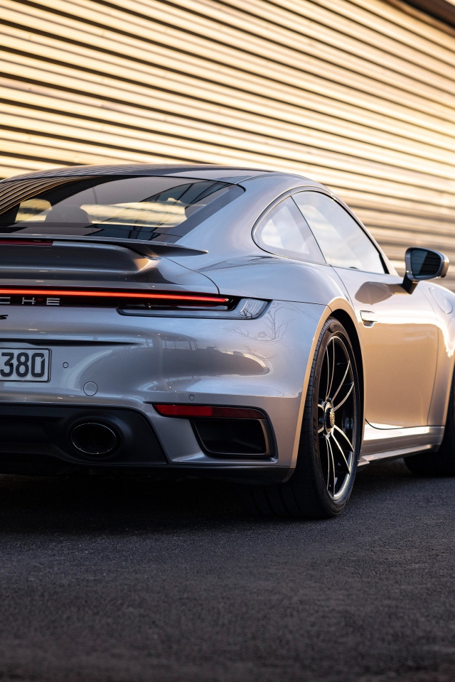 Серебристый автомобиль Porsche 911 Turbo S 2020 года у гаража