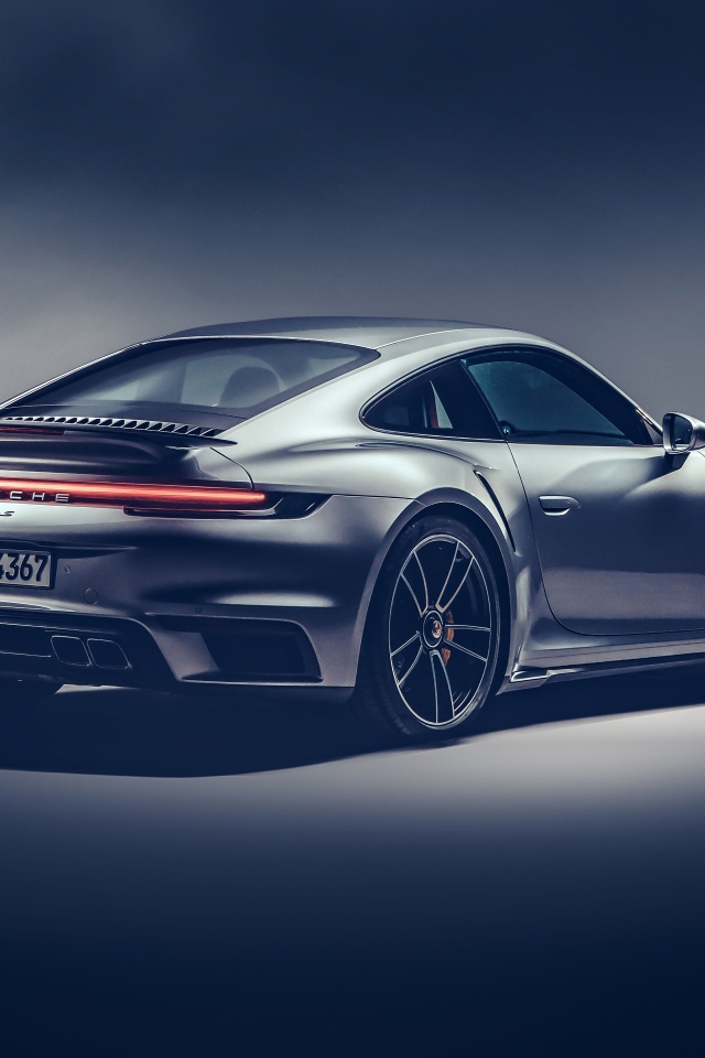 Автомобиль Porsche 911 Turbo S 2020 года на сером фоне вид сзади