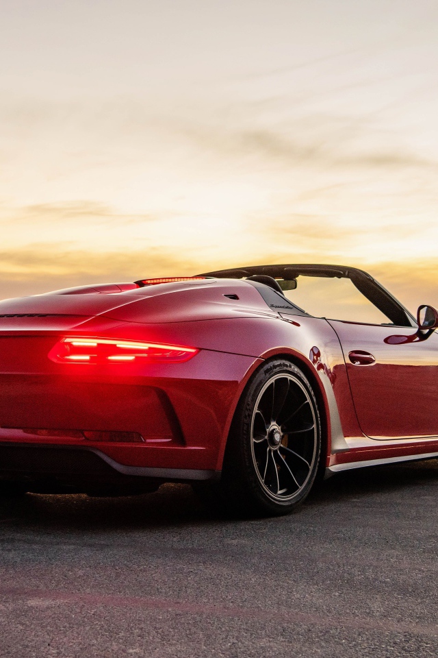 Красный автомобиль Porsche 911 Speedster, 2019 года у моря на закате