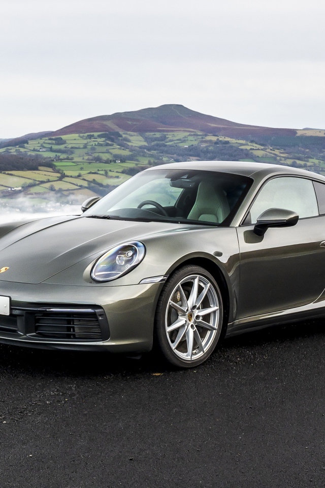 Серебристый автомобиль Porsche 911 Carrera на фоне холмов