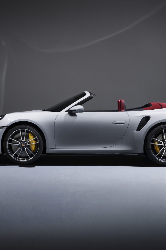 Белый автомобиль Porsche 911 Turbo S Cabriolet 2020 года на сером фоне