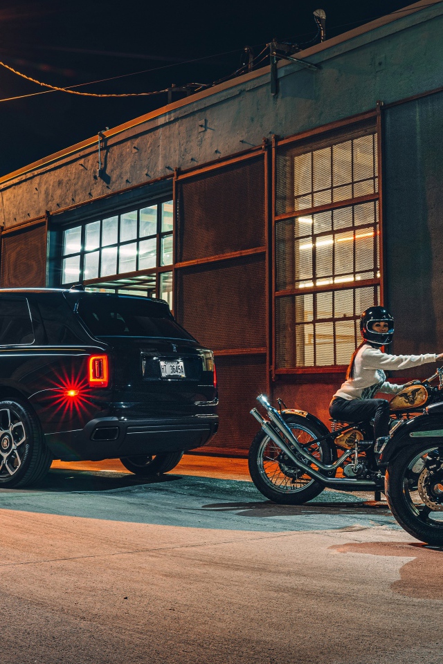 Черный автомобиль Rolls-Royce Cullinan, 2020 года у гаража с байкерами