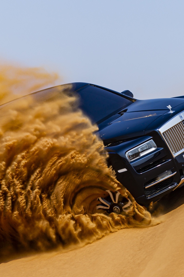 Черный Rolls-Royce Cullinan дрифтует по песку 