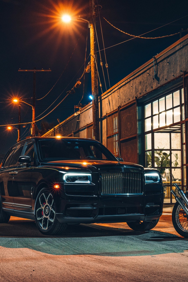 Черный стильный автомобиль Rolls-Royce Cullinan на улице города с байкерами