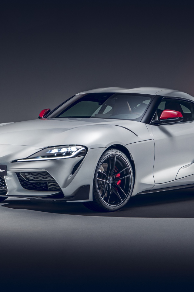 Серебристый автомобиль Toyota GR Supra 2L 2020 года на сером фоне