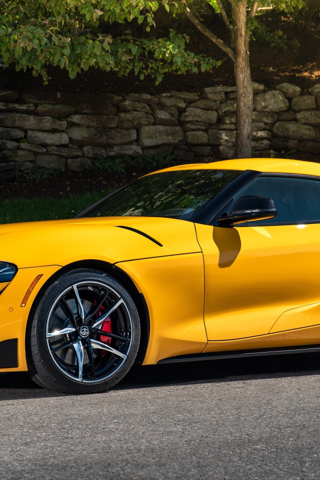 Желтый автомобиль Toyota GR Supra,ю 2021 года у стены