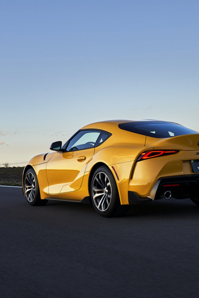 Желтый автомобиль Toyota GR Supra, 2021 года на трассе вид сзади
