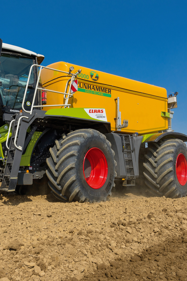 Большой комбайн пашет поле под голубым небом