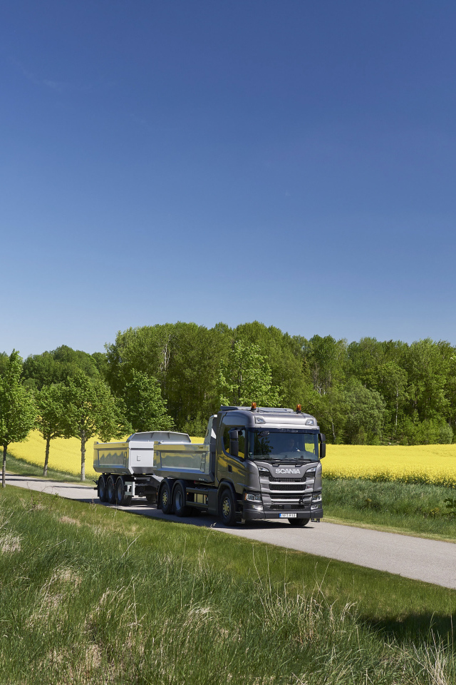 Грузовик Scania Trucks на трассе у поля