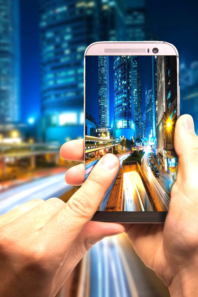 Мужчина делает фото ночного города на смартфон 