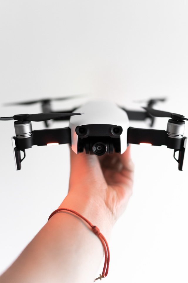White quadrocopter in hand on a white background