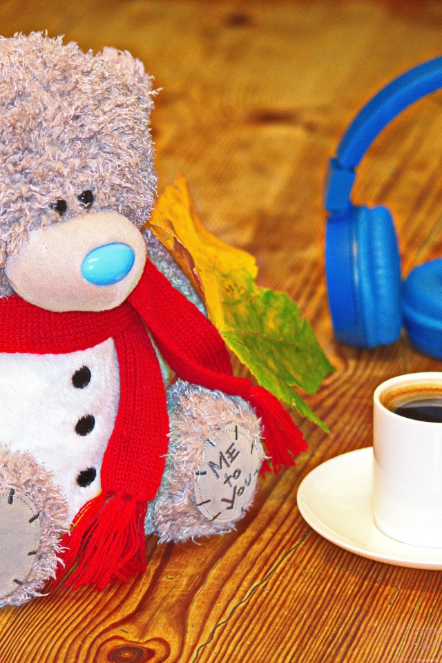 Медведь на столе с чашкой кофе и наушниками 