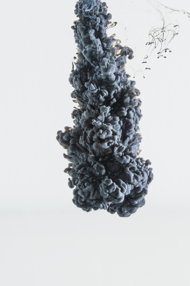 Черная краска растворяется в воде на белом фоне 