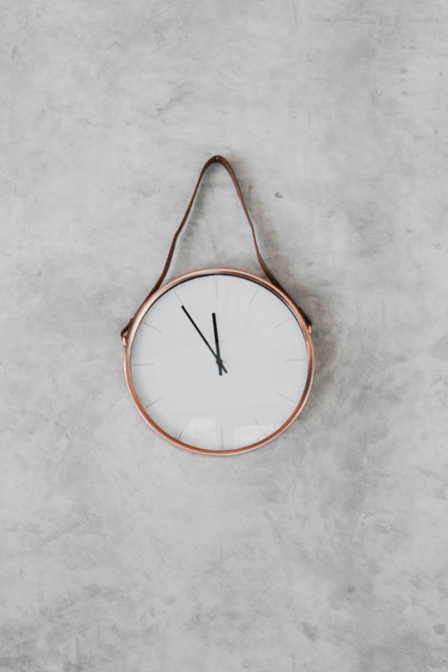 Clock with black arrows hang on a gray wall