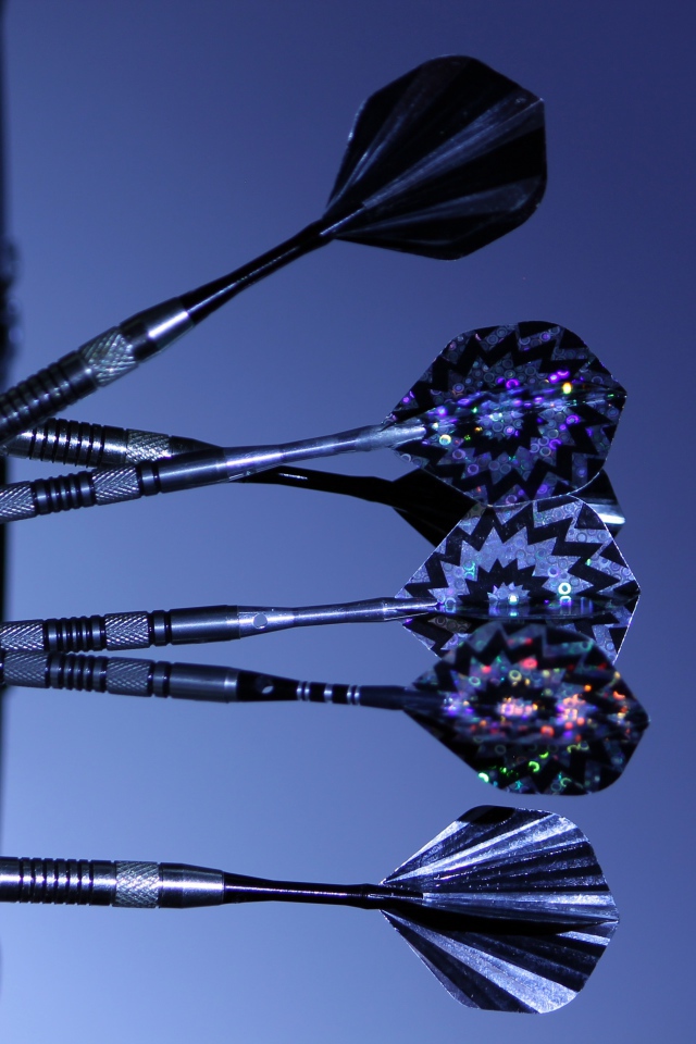 Дротики в доске для дартс на синем фоне 