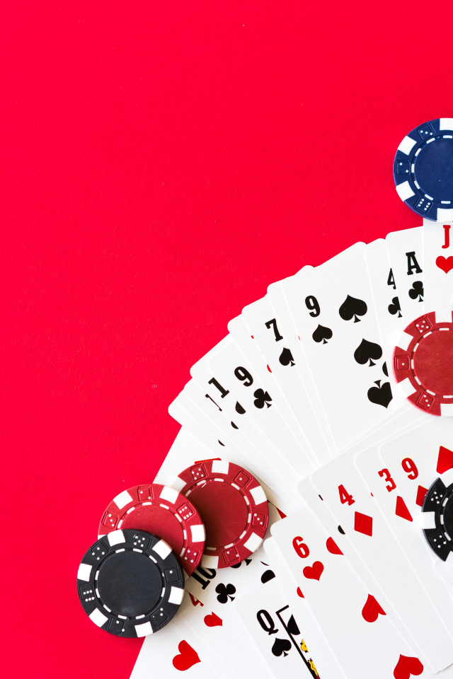 Колода карт и фишки для игры в покер на красном фоне