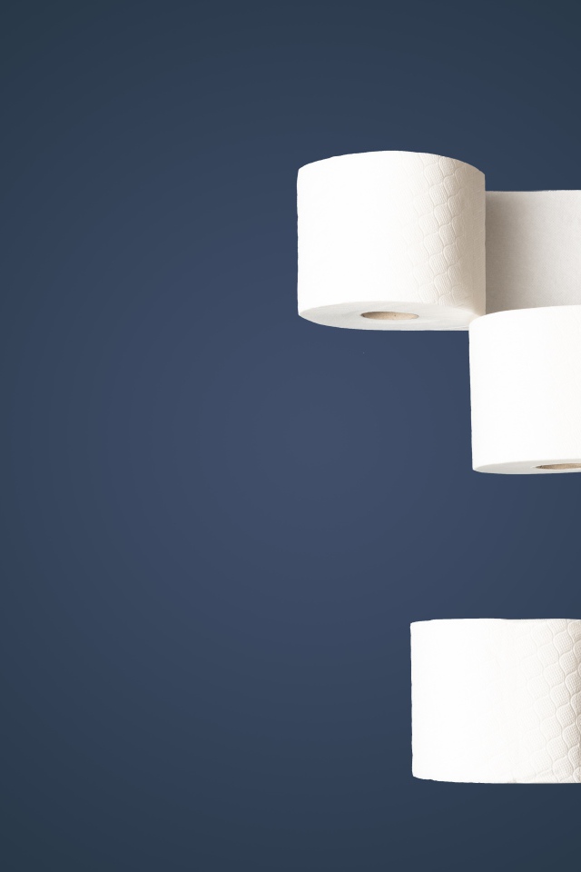 Четыре рулона белой туалетной бумаги на сером фоне