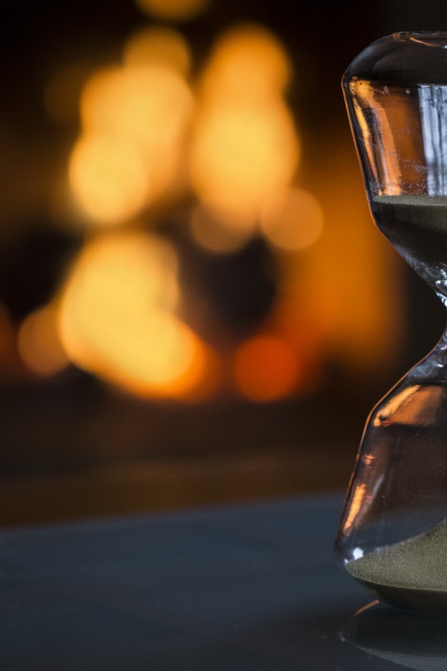 Стеклянные песочные часы на столе 