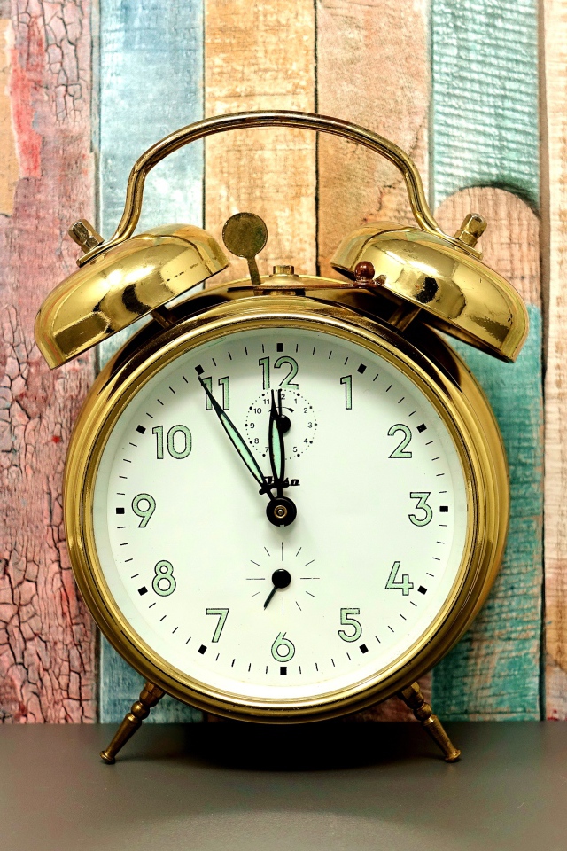 Золотой будильник стоит у стены 