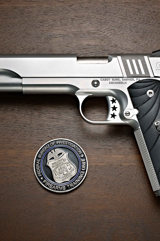 Пистолет Cabot 1911 лежит на столе с очками и жетоном 