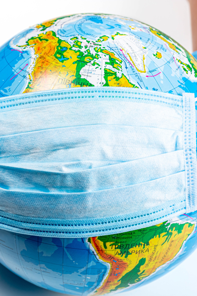 Руки одевают маску от коронавируса на глобус 