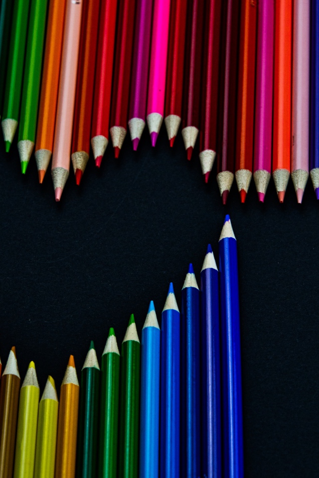 Сердце из разноцветных карандашей на черном фоне