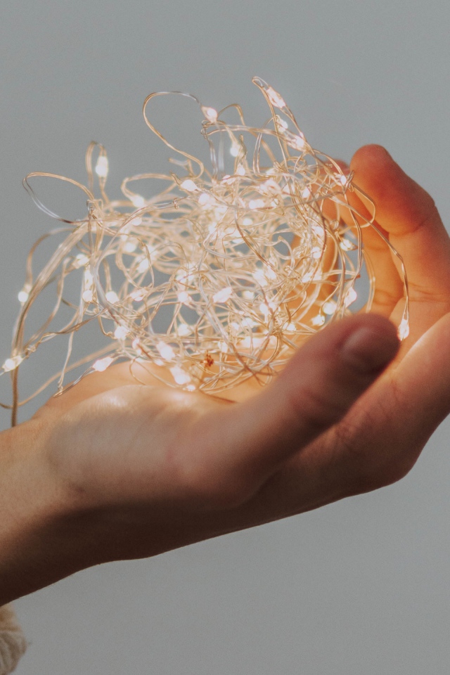 Включенная гирлянда в руке на сером фоне