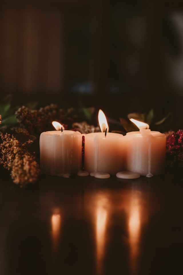 Зажженные свечи с цветами на полу