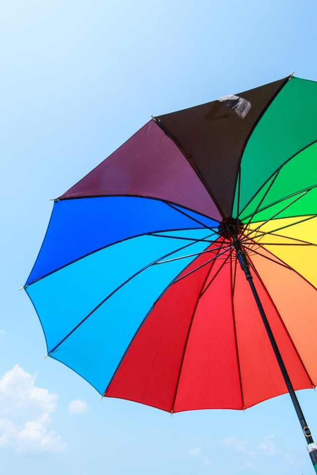 Разноцветный зонт на фоне голубого неба 