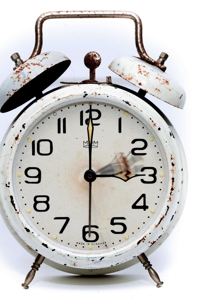 Старый потертый будильник на белом фоне