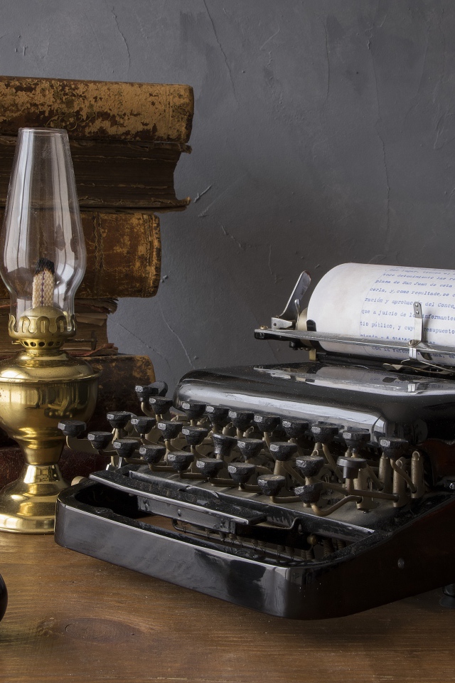 Старая печатная машинка, книги, керосиновая лампа и трубка на столе 