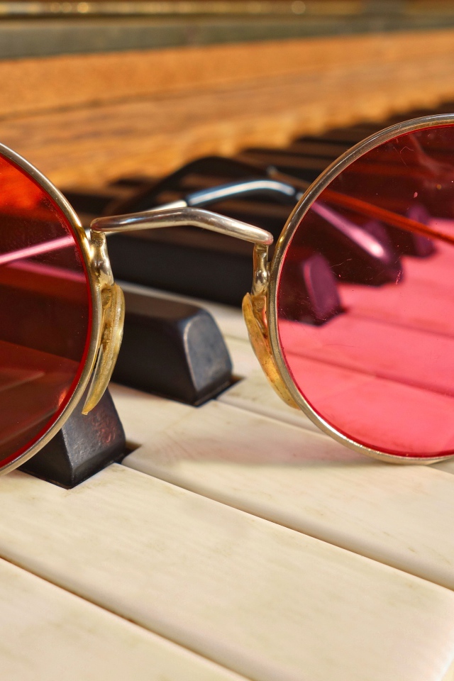 Розовые очки лежат на клавишах рояля