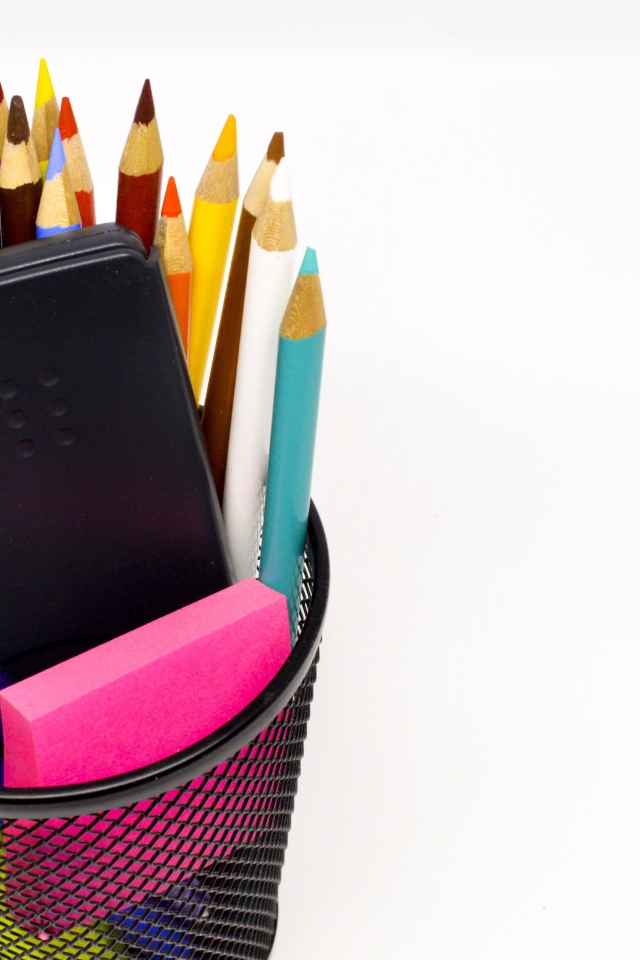 Канцелярские предметы в черном стакане на белом фоне 